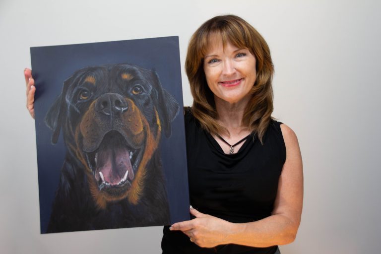 Patti Trout holding pet portrait of Rottweiler